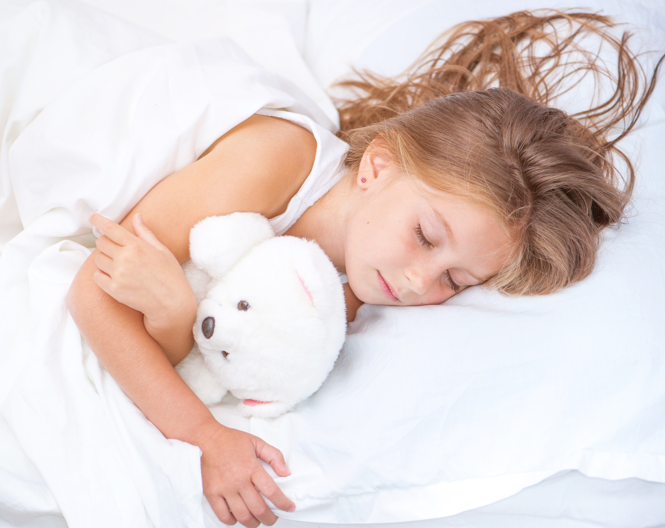 kleines Mädchen im Bett mit Teddybär